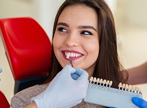 Woman's smile compared with tooth color chart