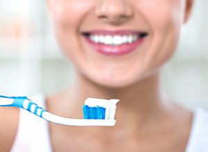 Woman holding up toothbrush with toothpaste