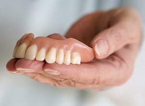 Hand holding full dentures